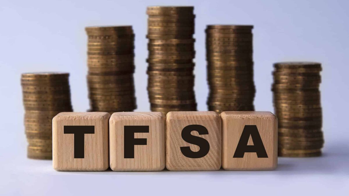 TFSA (Tax free savings account) acronym on wooden cubes on the background of stacks of coins